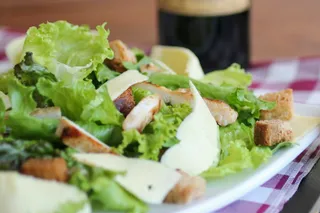 A Caesar salad with croutons and shaved parmesan