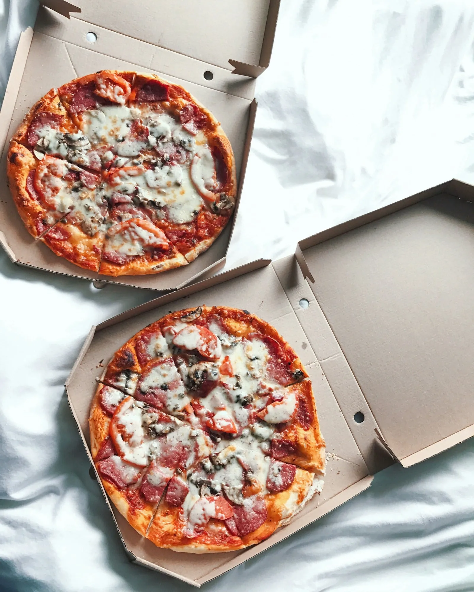 Two pizzas in open takeout boxes