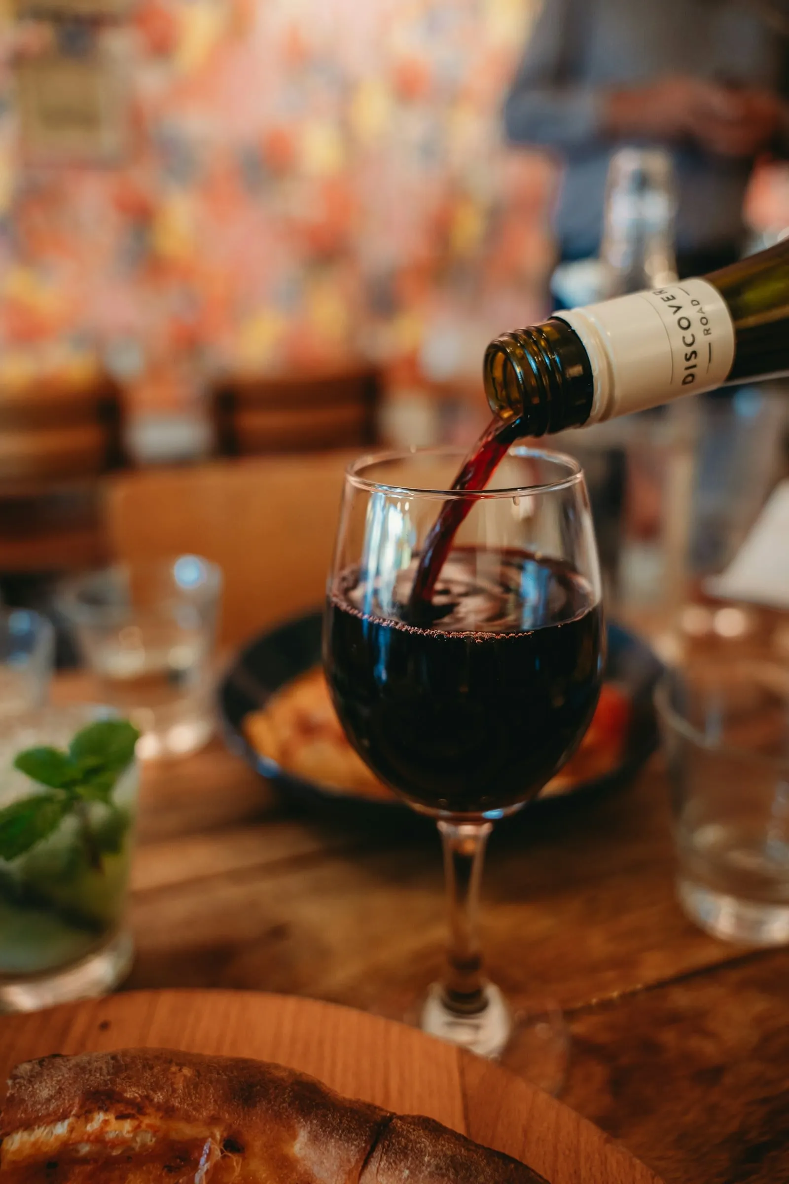 Red wine being poured into a glass at a wooden table