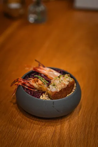 Grilled prawns in a dark bowl on a wooden table
