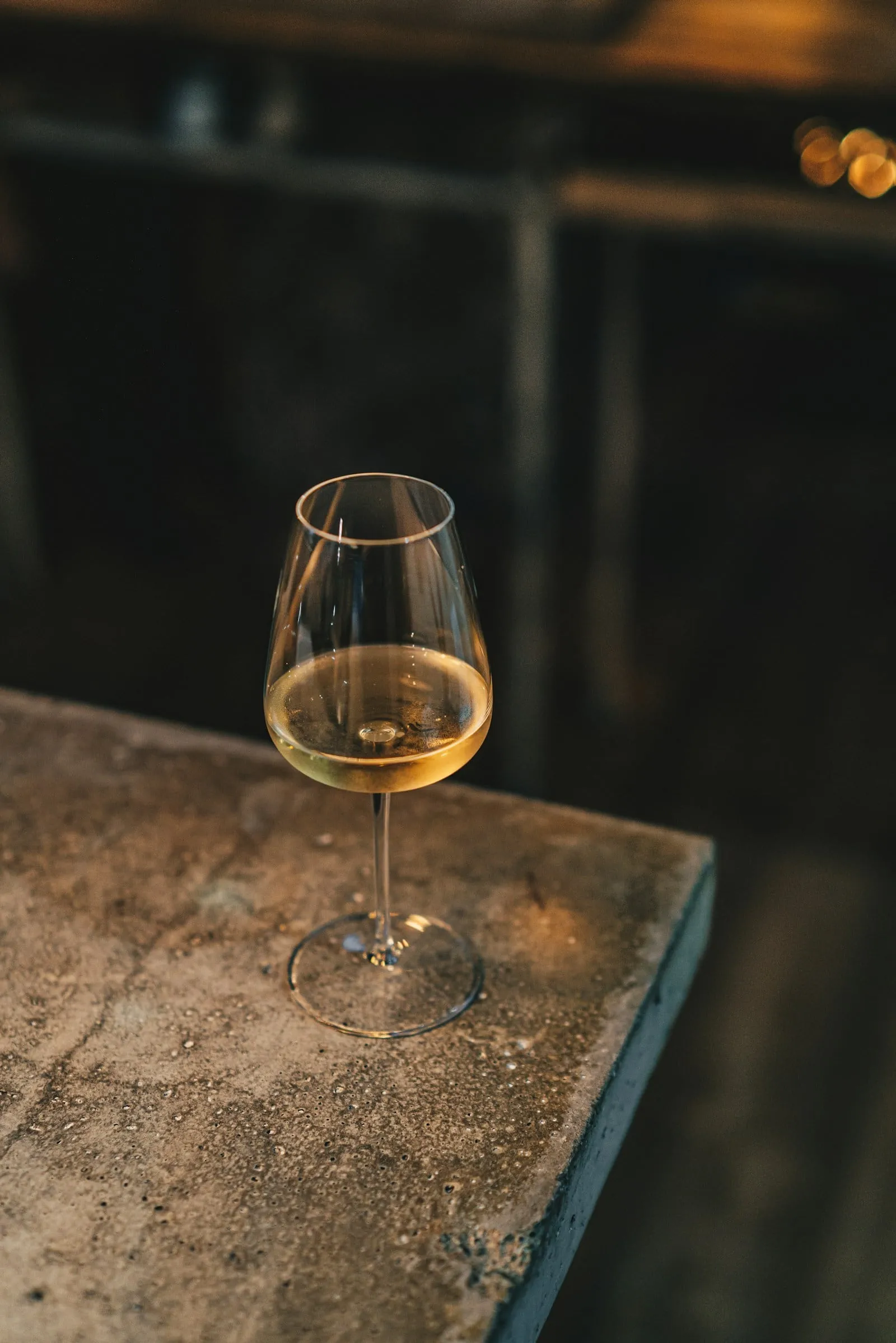 A single glass of white wine on a stone ledge