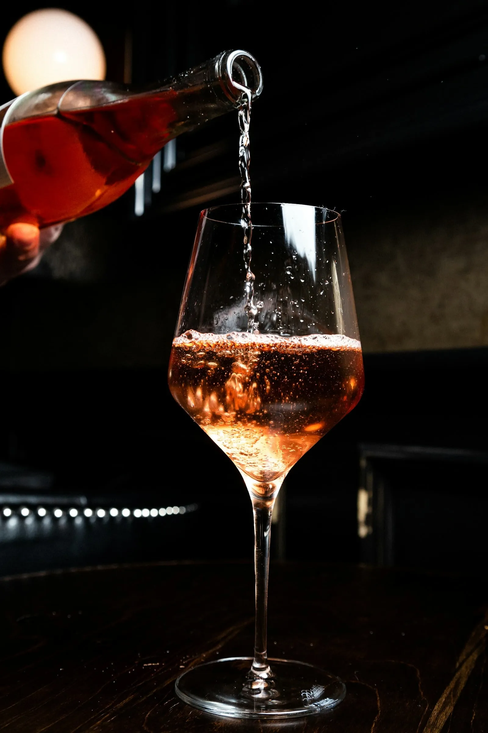 Rosé being poured into a glass in a dark room