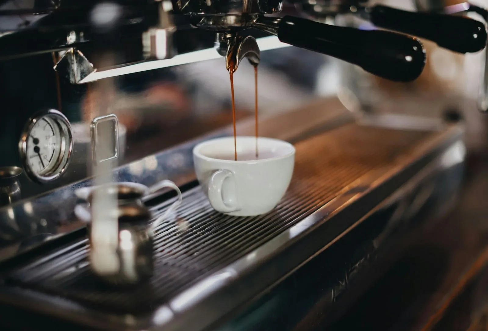 An espresso shot pouring into a white cup
