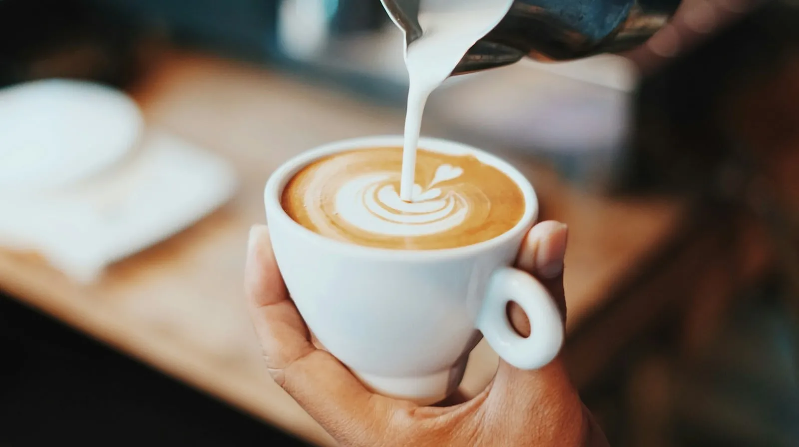 A latte with milk being poured into it