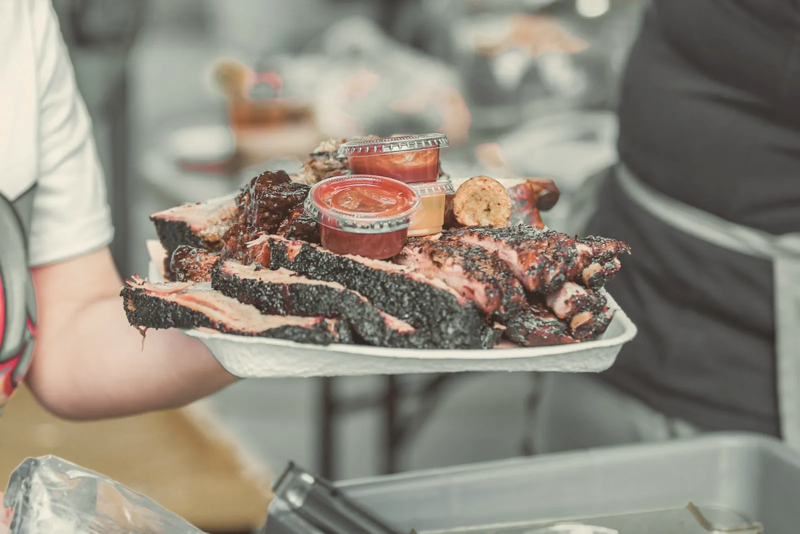 A tray of sliced brisket and ribs being carried out