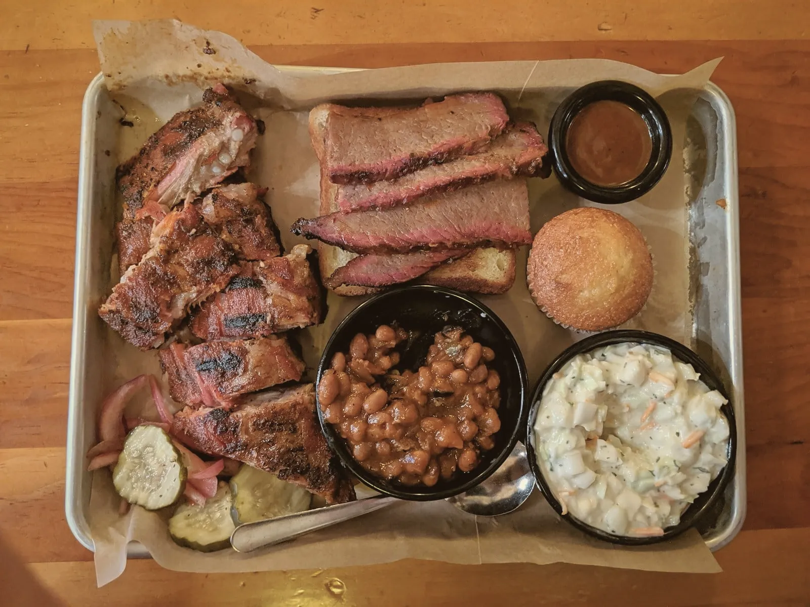 A barbecue tray with brisket, ribs, beans and slaw seen from above