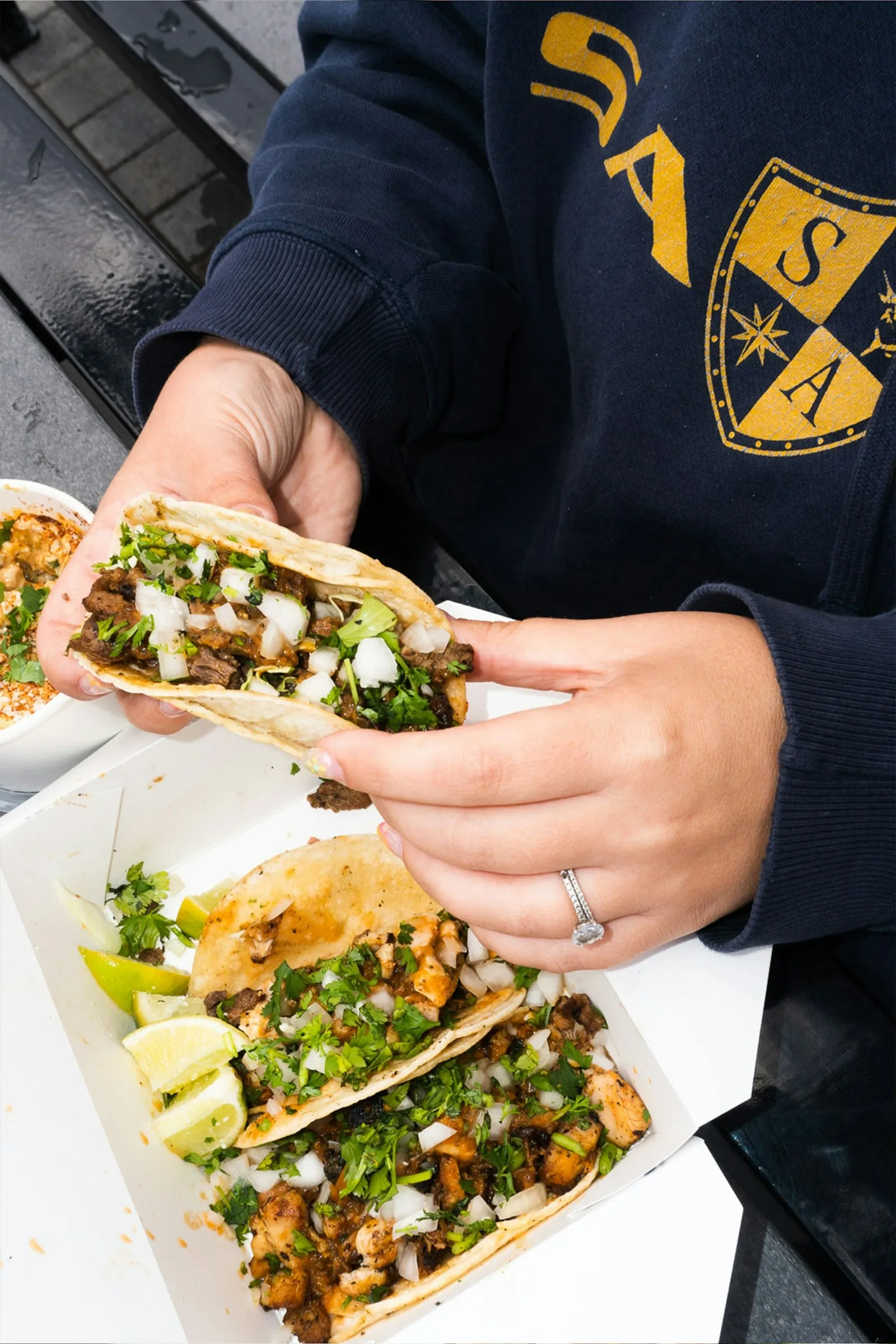 Someone holding two tacos in a paper tray