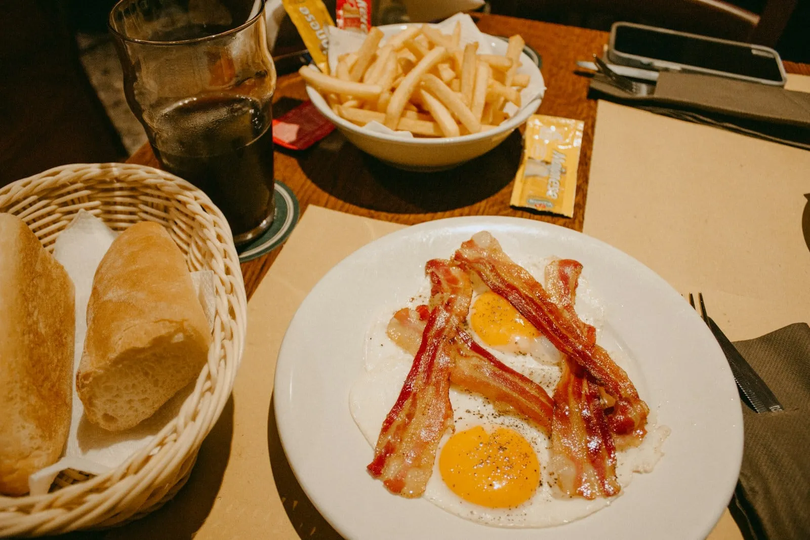 Bacon and fried eggs with a basket of fries and toast