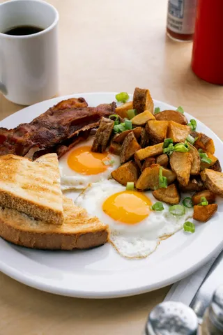 Two fried eggs with bacon, home fries and toast