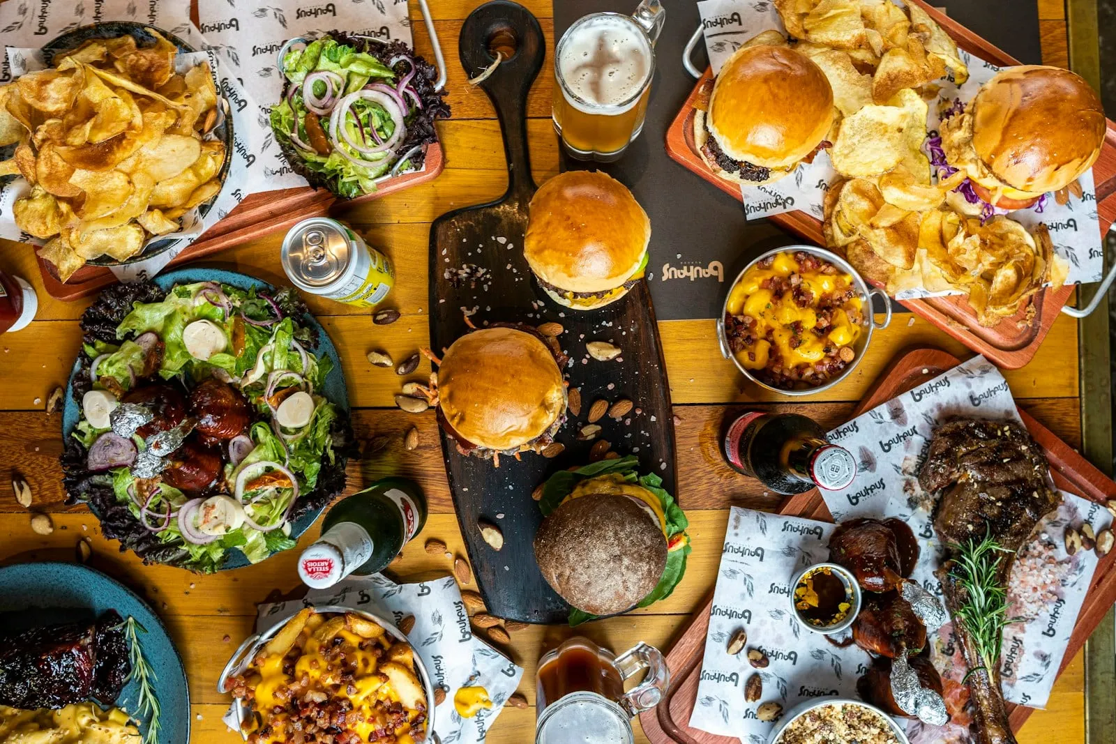 A table covered with burgers, fries and salads seen from above